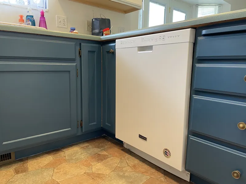 Blue painted lower cabinets with a white dishwasher