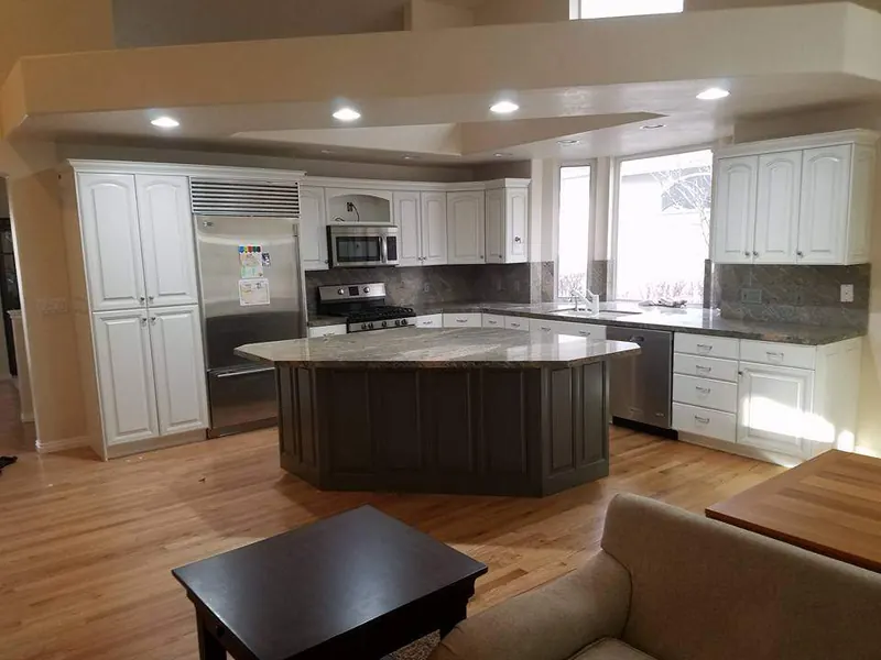 Open kitchen with white painted cabinets and a dark-finished island