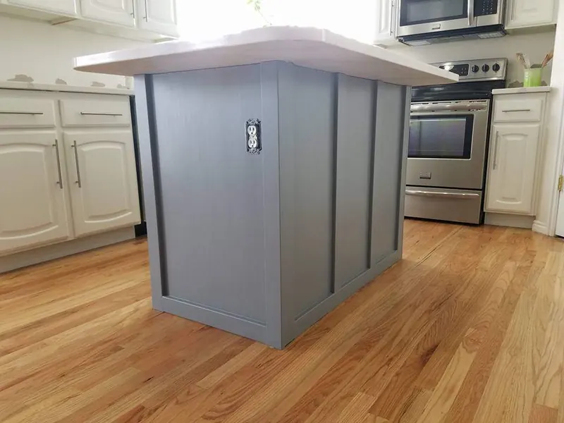 Kitchen island painted a deep slate blue next to white perimeter cabinets
