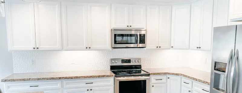 Bright white painted kitchen cabinets with stainless appliances